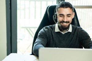 A friendly customer support agent wearing headphones, working in an office environment.